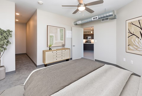 A bedroom with a bed, dresser, and ceiling fan.