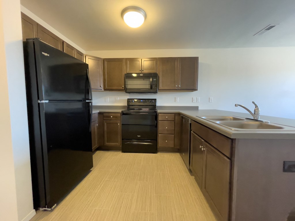 an empty kitchen with black appliances and wooden cabinets