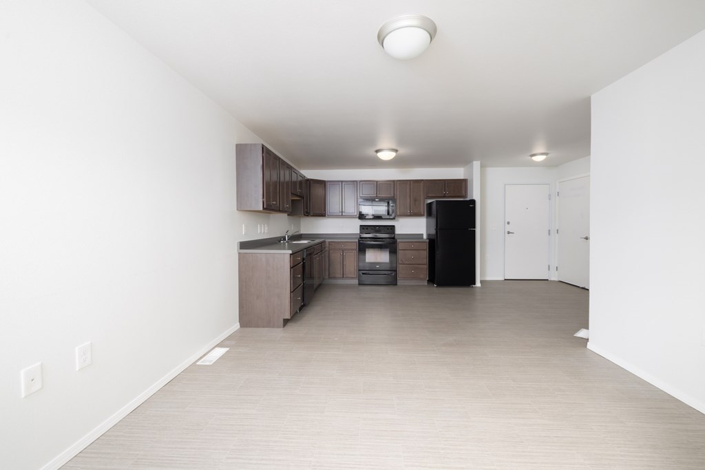 A kitchen with a black fridge and white walls.