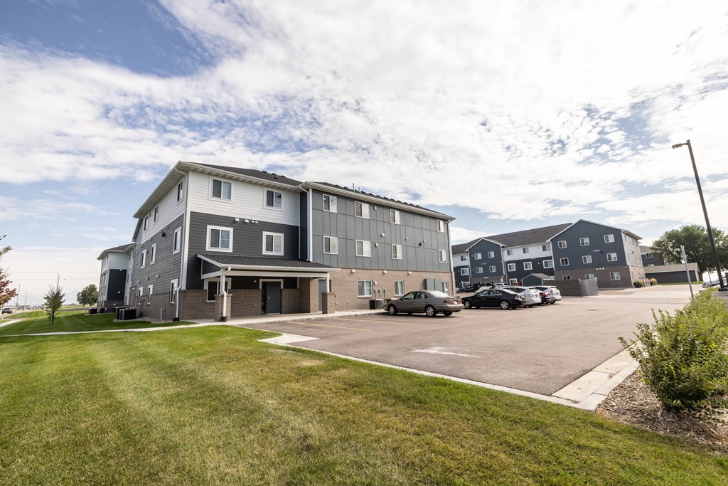 A large grey building with a parking lot in front.