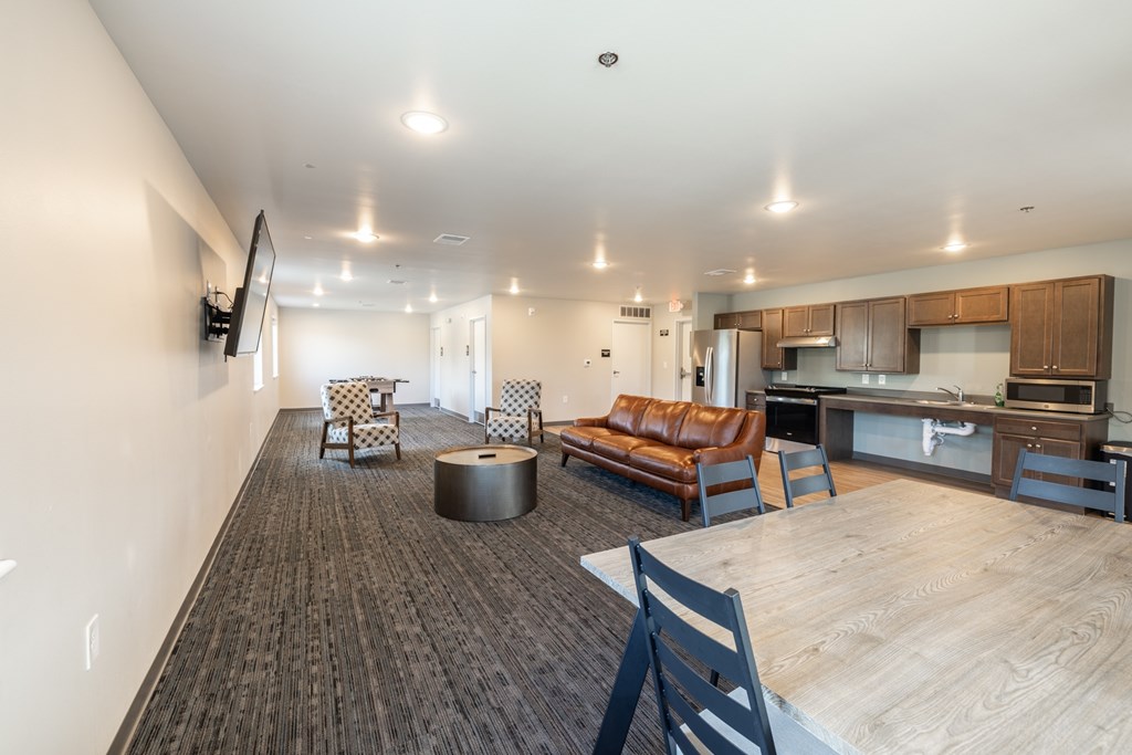 A modern living room with a brown leather couch and a wooden floor.