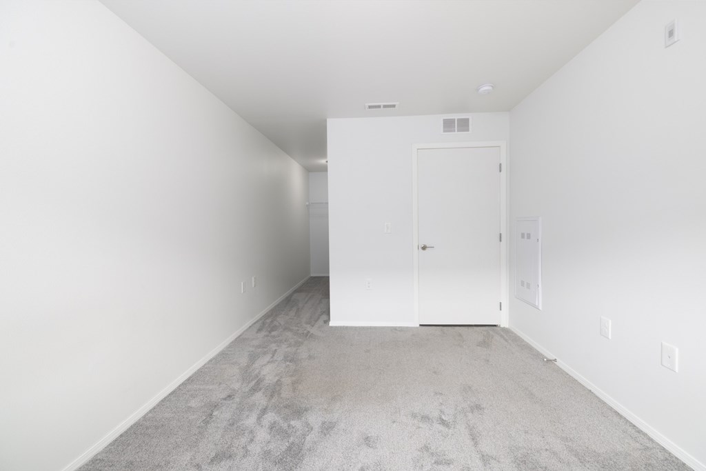 A room with a carpeted floor and a white door.