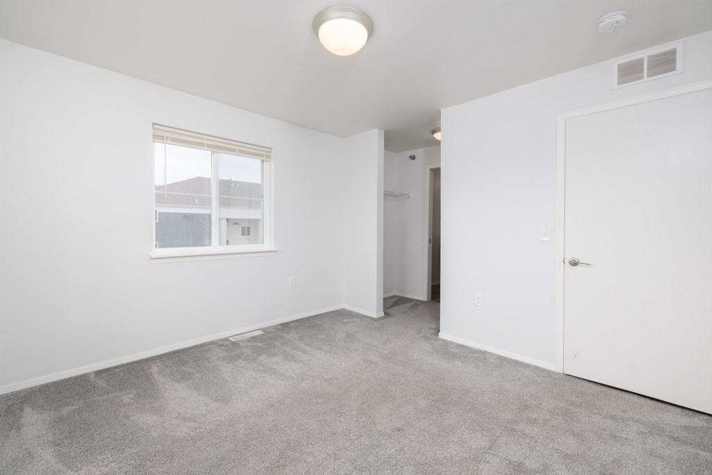 A room with a carpeted floor and a window.