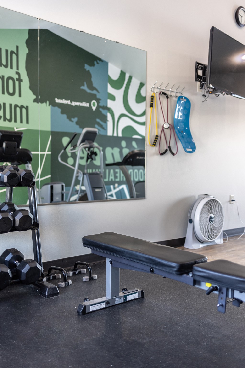 a workout room with weights and a yoga bench in front of a mirror