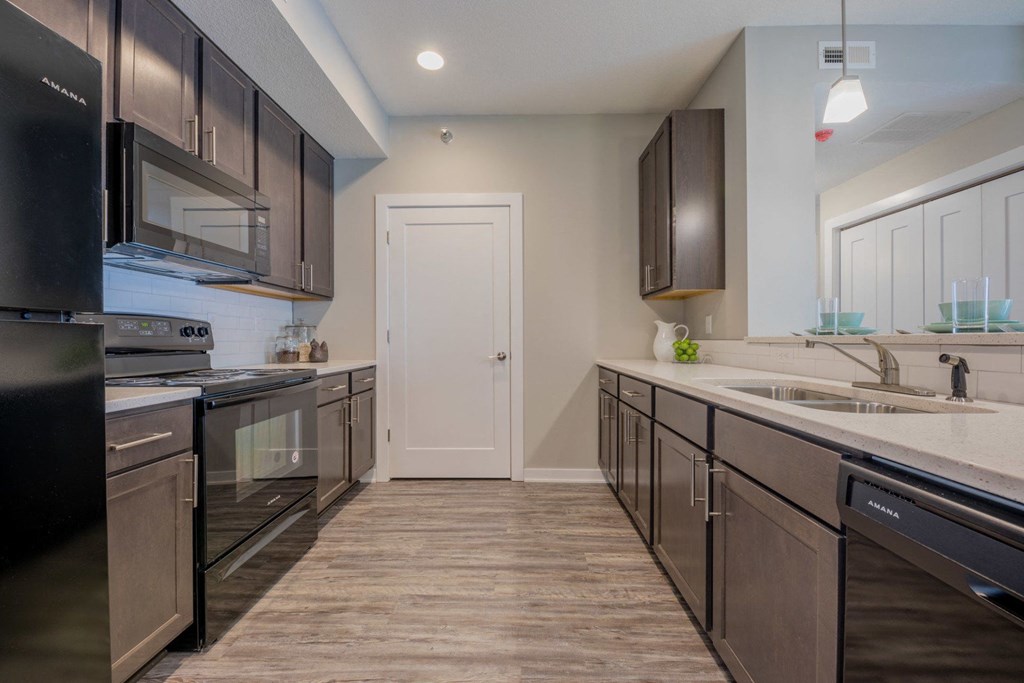an empty kitchen with stainless steel appliances and wood flooring