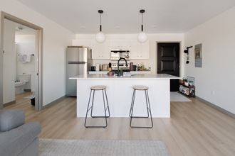 a white kitchen with two bar stools in front of a white counter top