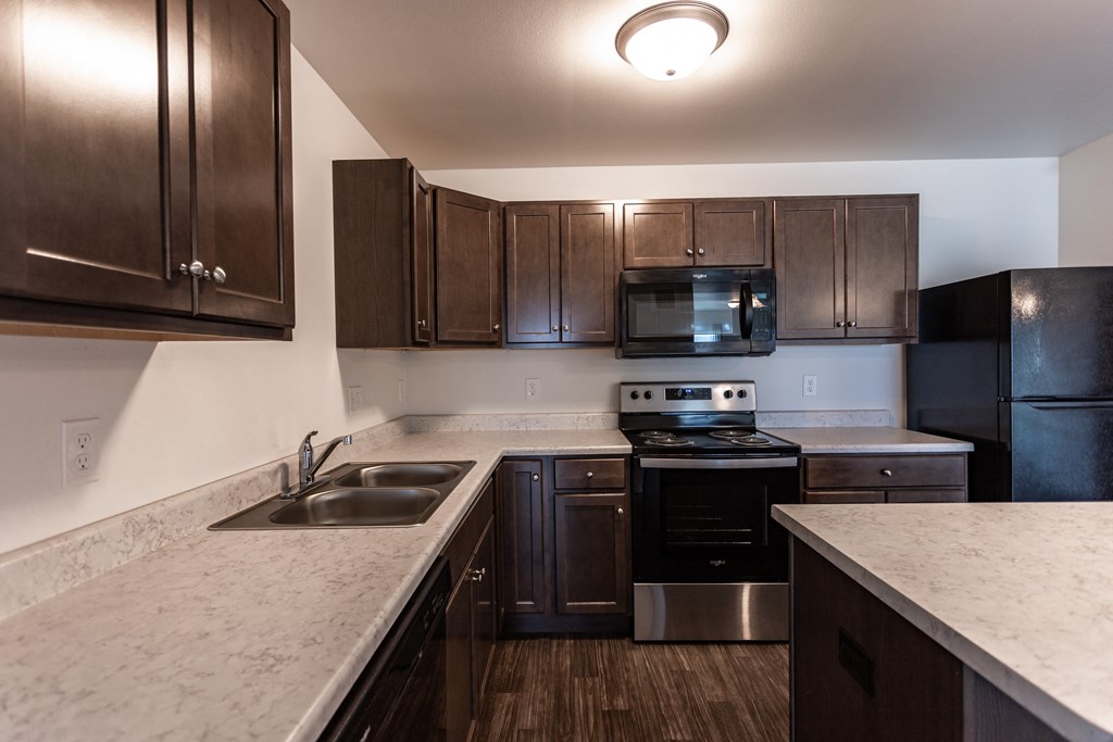 an empty kitchen with dark wood cabinets and marble counter tops