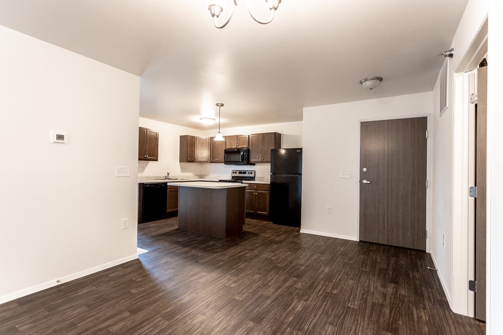 a view of a kitchen and a living room with wood flooring and a door