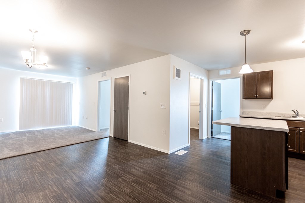 an empty living room and kitchen with wood floors and white walls