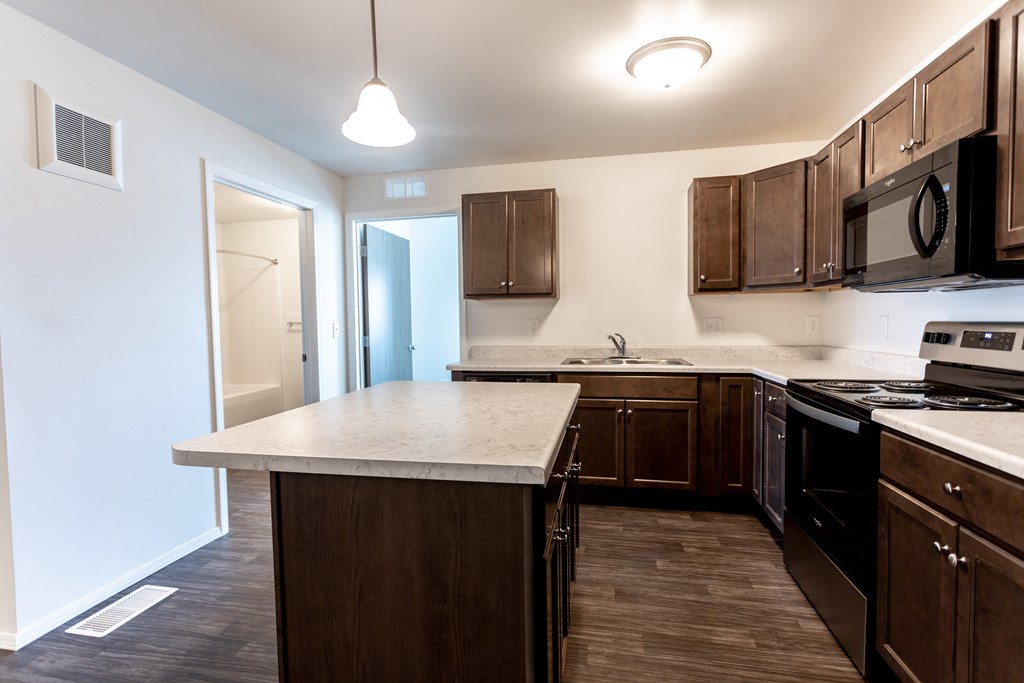 an empty kitchen with a marble counter top and wooden cabinets