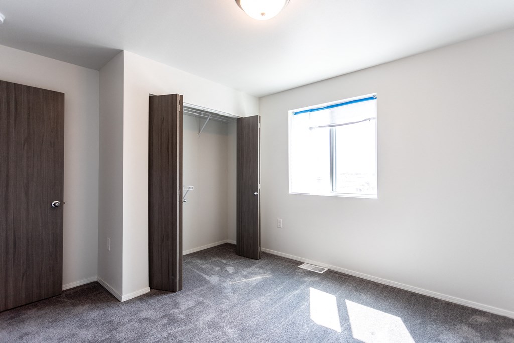 an empty room with a door to a closet and a window