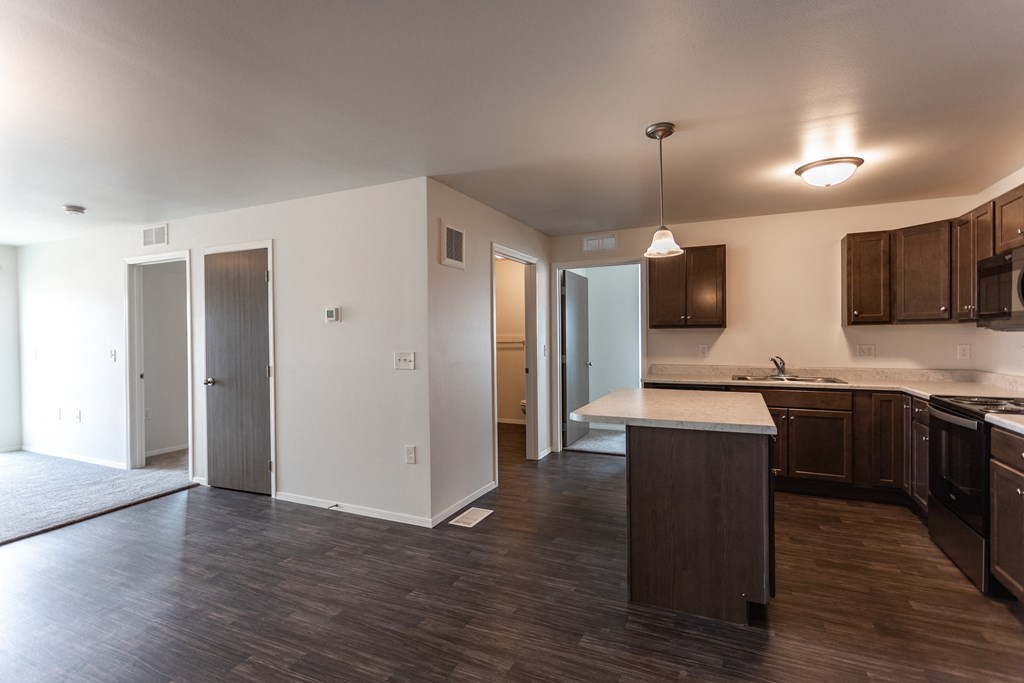an empty kitchen and living room with wood flooring and white walls
