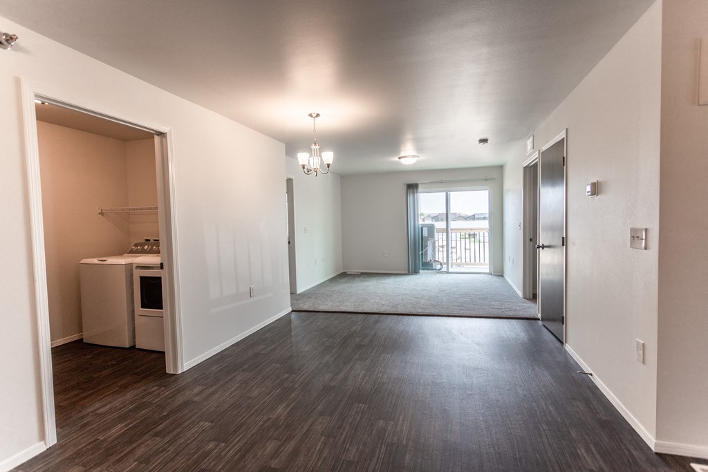 an empty living room and kitchen with a door to a balcony