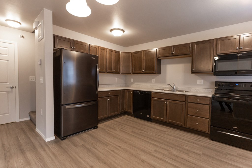 an empty kitchen with black appliances and wooden cabinets