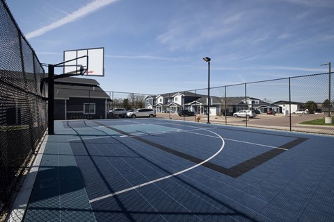 A basketball court with a black fence and a basketball hoop.