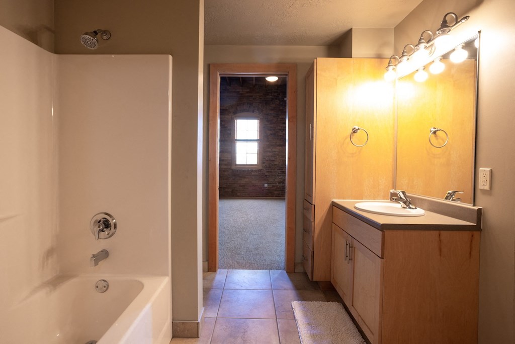 the view of a bathroom with a tub and a sink and a mirror