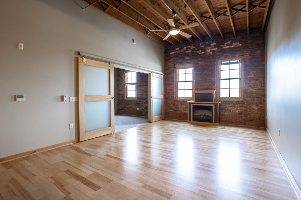 an empty living room with a wood floor and brick walls