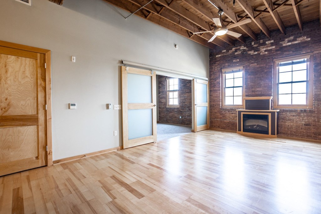an empty living room with a fireplace and wood flooring