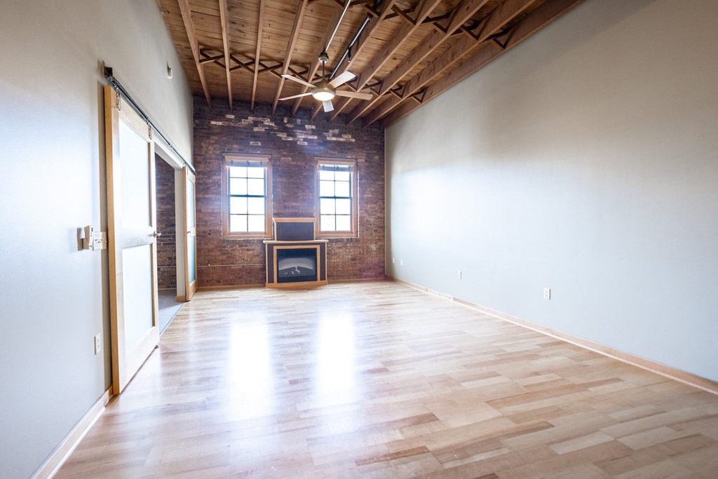 an empty room with wooden floors and a brick wall