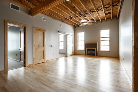an empty living room with wooden floors and a fireplace