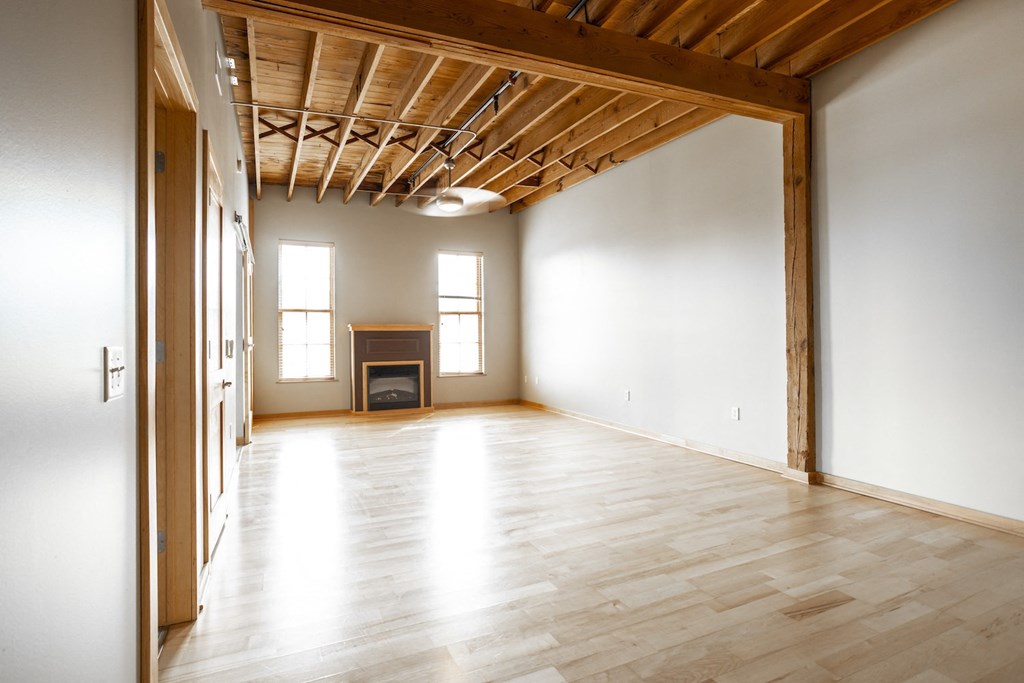 an empty living room with wood floors and a fireplace