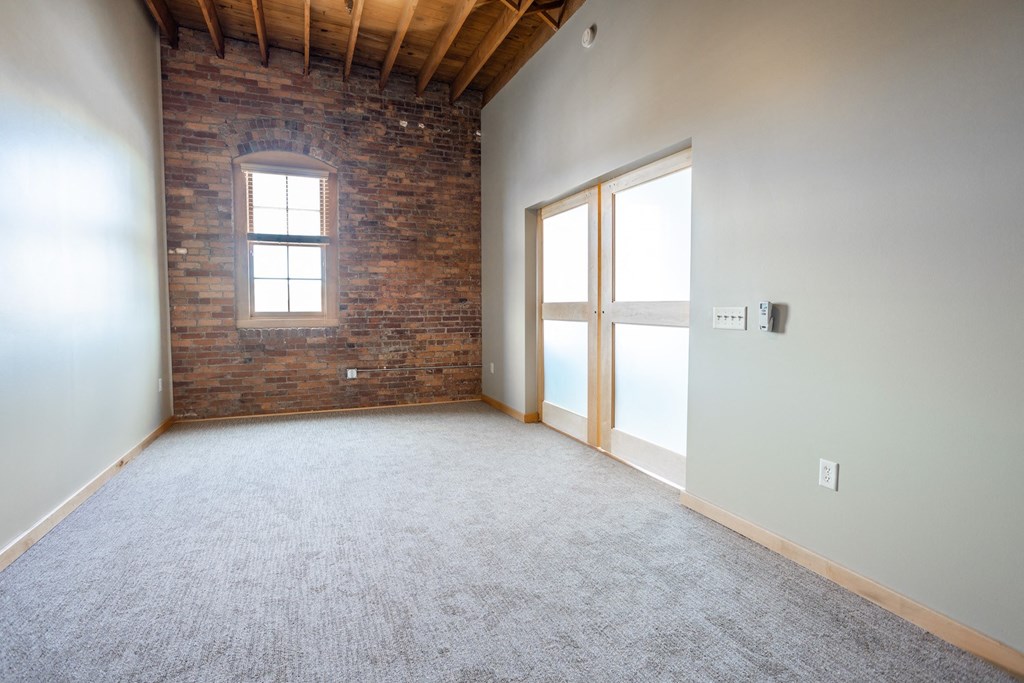 an empty room with a brick wall and a window