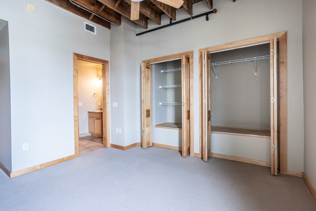 an empty room with two closets and a door to a bathroom