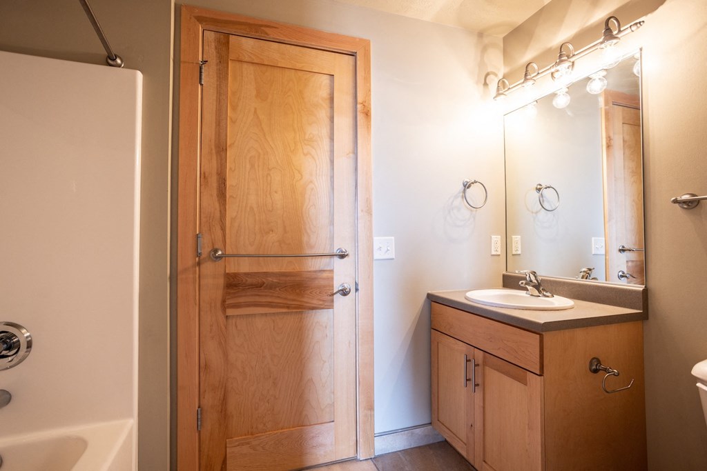 a bathroom with a wooden door and a sink and a shower