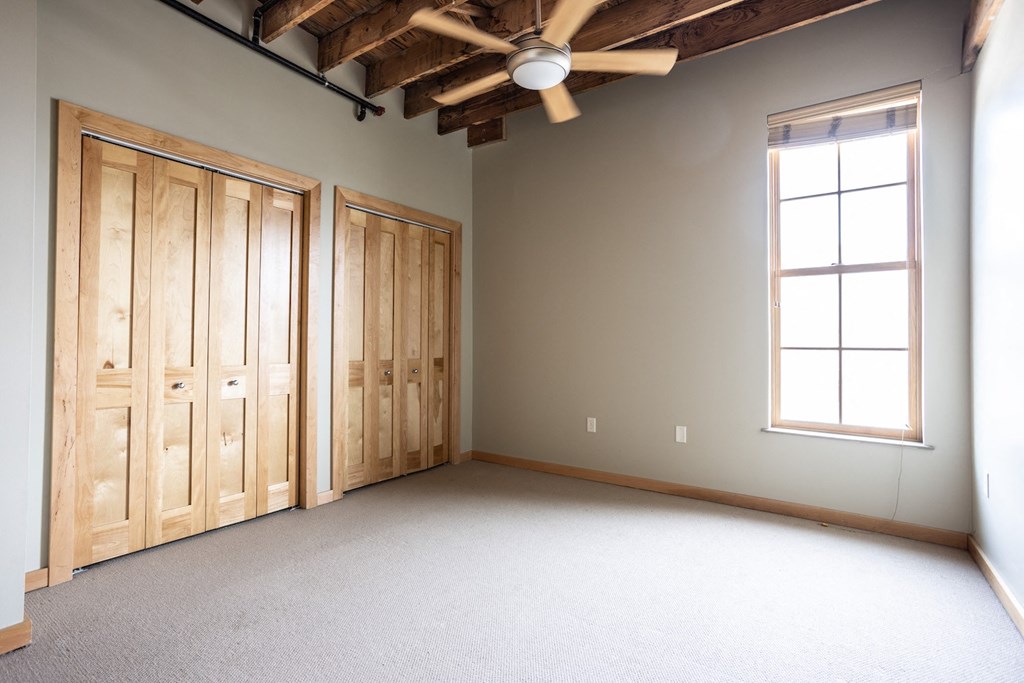 an empty room with two doors and a ceiling fan