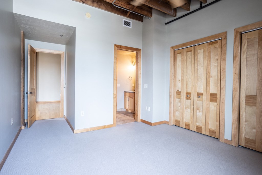 an empty room with three doors and a doorway to a bathroom
