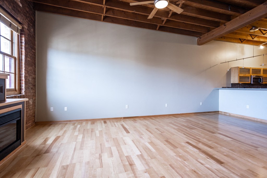 an empty living room with wood floors and a white wall