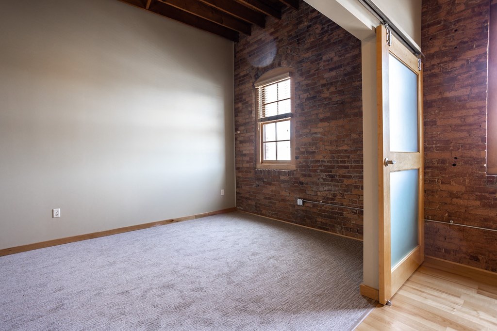 an empty living room with a brick wall and a window