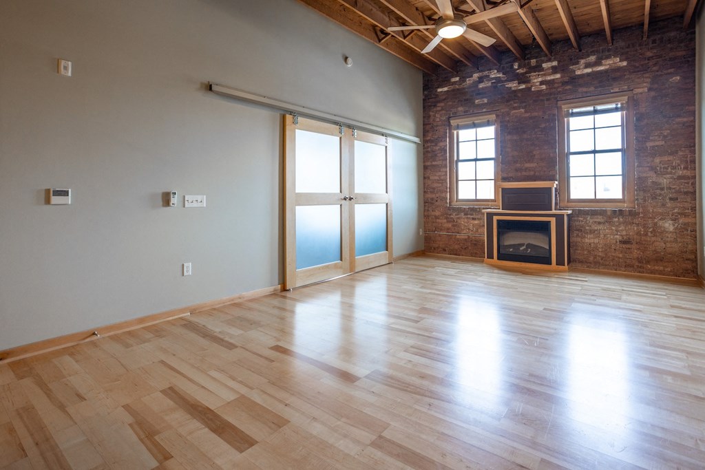 an empty living room with a fireplace and wooden floors