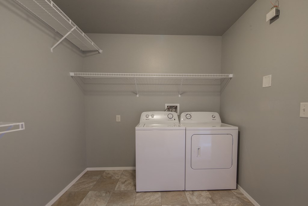an empty laundry room with a washer and dryer and a white dryer