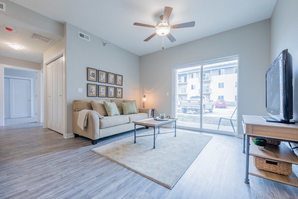 a living room with a couch and a ceiling fan and a tv