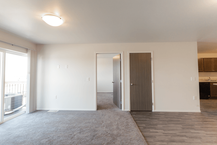 an empty living room with a door to a bedroom and a window