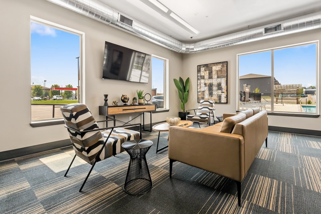 A living room with a striped chair, a brown couch, and a small table with a vase on it.