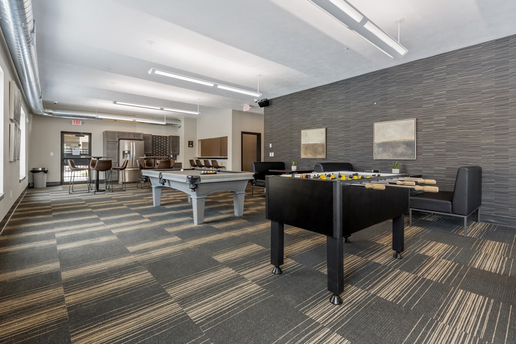 A billiard table is in the middle of a room with a carpeted floor.