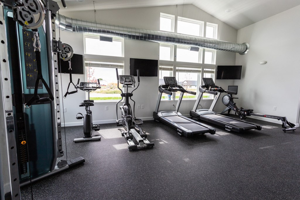 a gym with cardio equipment and windows in a building