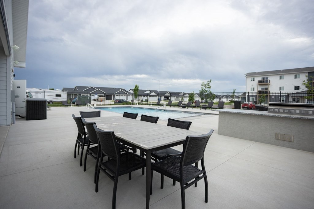 a patio with a dining table and chairs next to a pool