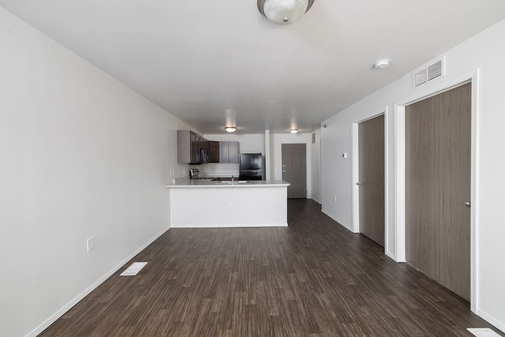 A spacious room with wooden flooring and white walls.