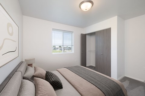A bedroom with a large bed and a window overlooking a green area.