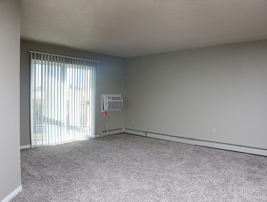 an empty living room with a large window and carpet