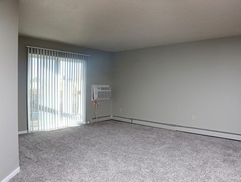 an empty living room with a large window and carpet