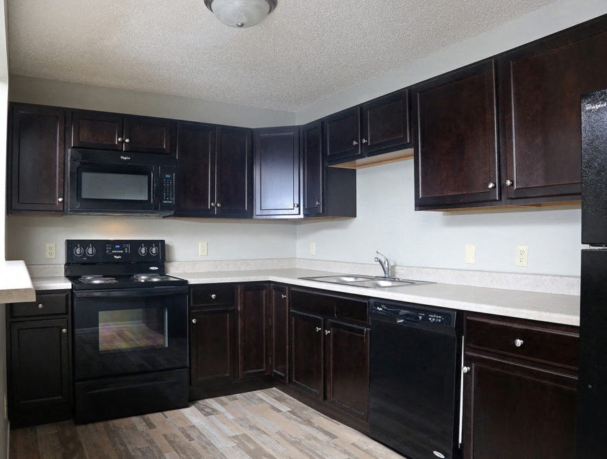 an empty kitchen with black appliances and wooden cabinets