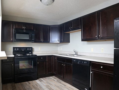 an empty kitchen with black appliances and wooden cabinets