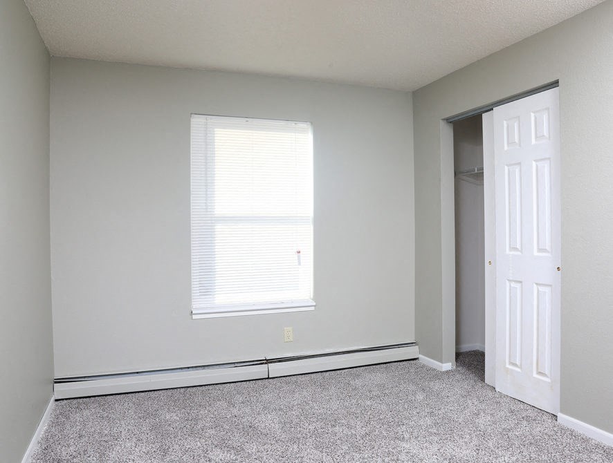 an empty room with a window and a closet