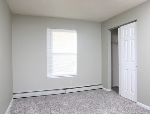an empty room with a window and a closet