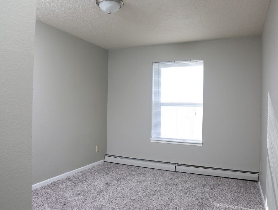 an empty room with a window and carpet
