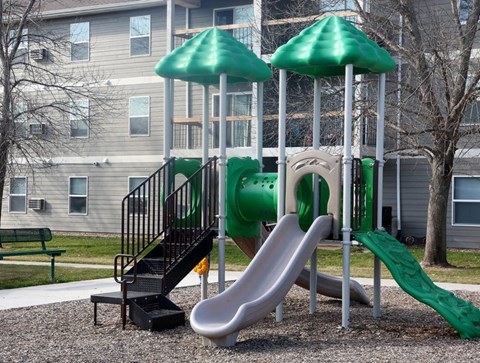 a playground with a slide and two green umbrellas